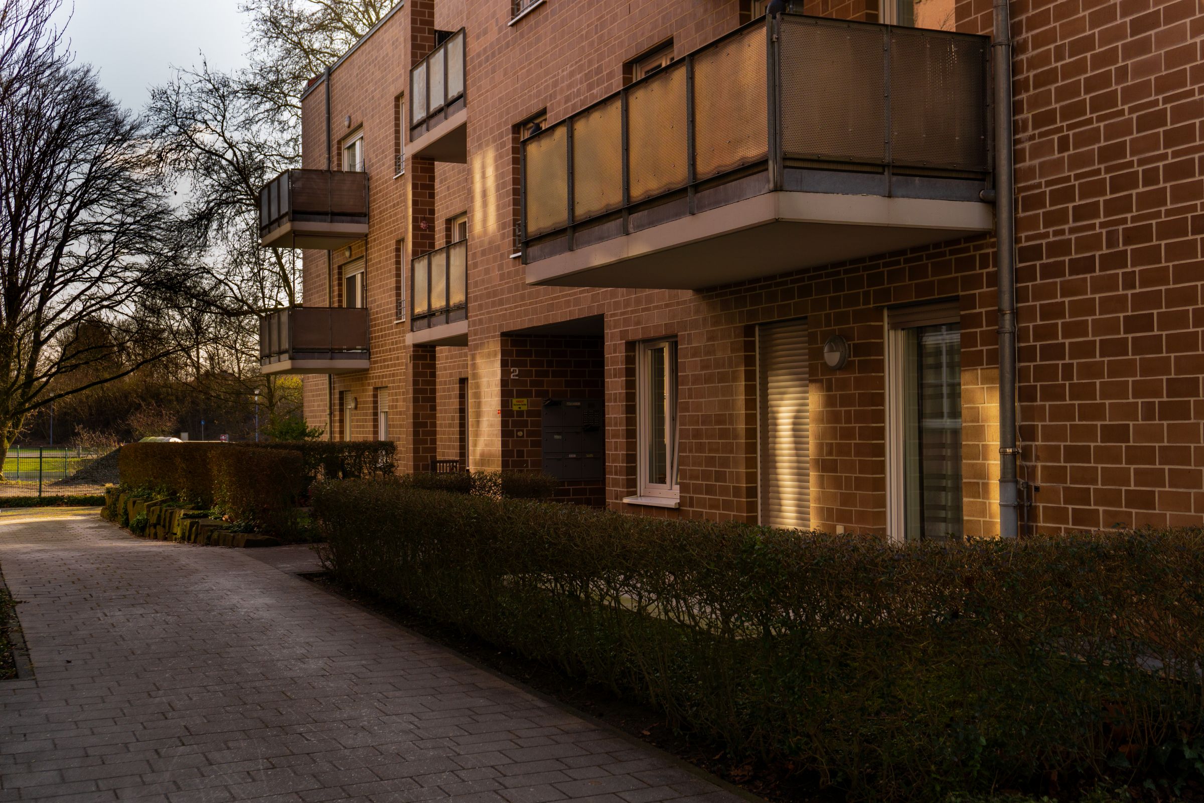 Vermietetes Mehrfamilienhaus aus Backstein mit Balkonen am Abend